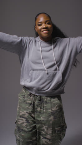 Vertical-Video-Full-Length-Studio-Portrait-Shot-Of-Young-Woman-Dancer-Dancing-In-Against-Grey-Background-In-Slow-Motion-1